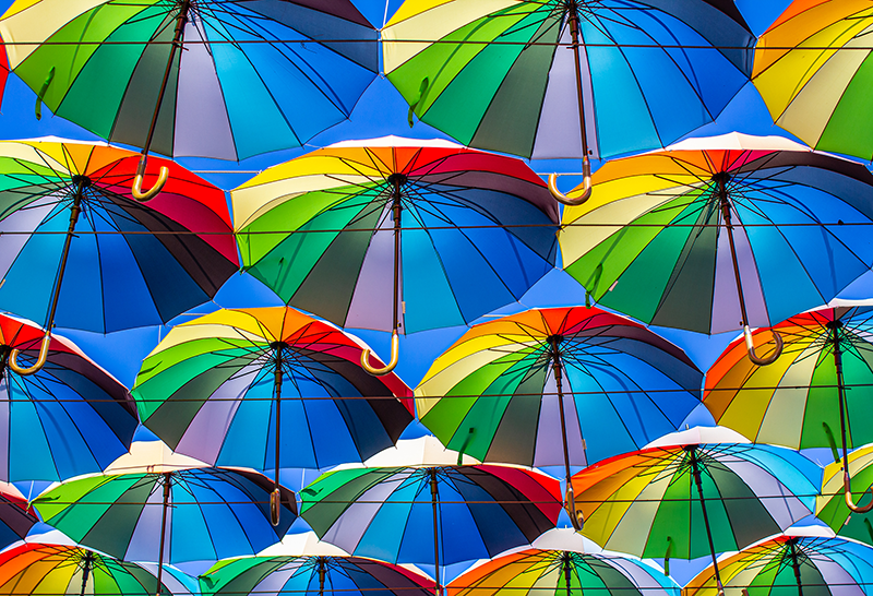 A group of rainbow patterned umbrellas.