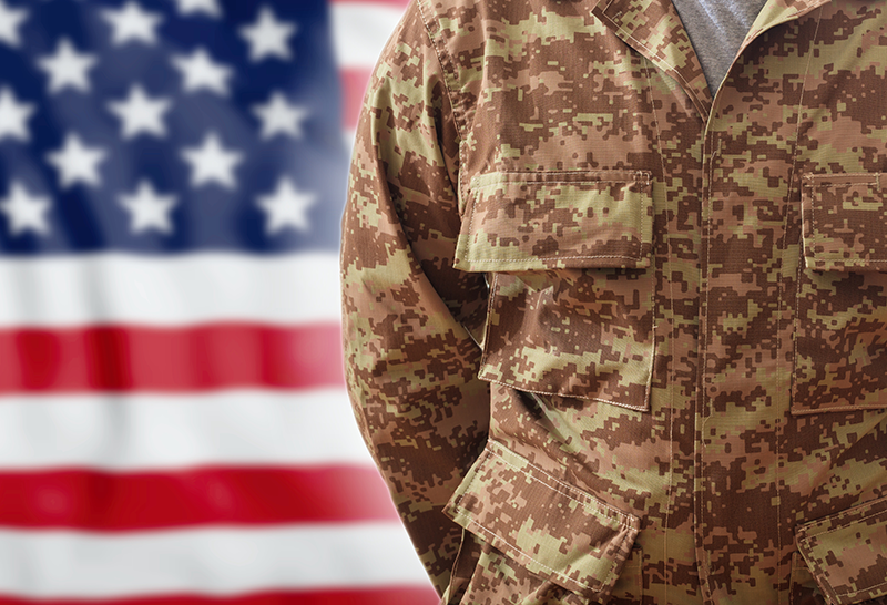 The torso of a person in military uniform and part of the flag of the United States.