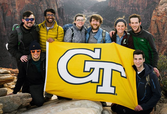 A group of GT students during a field trip holding a GT flag.