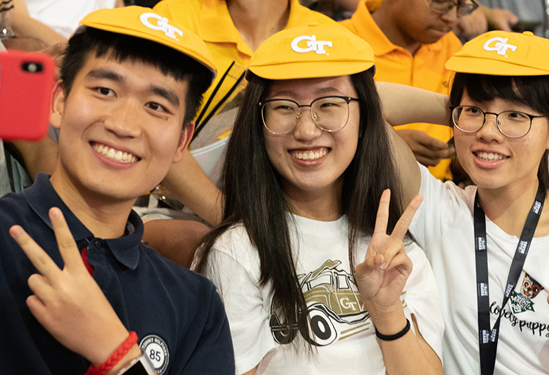 Three GT students wearing RAT caps while taking a selfie.